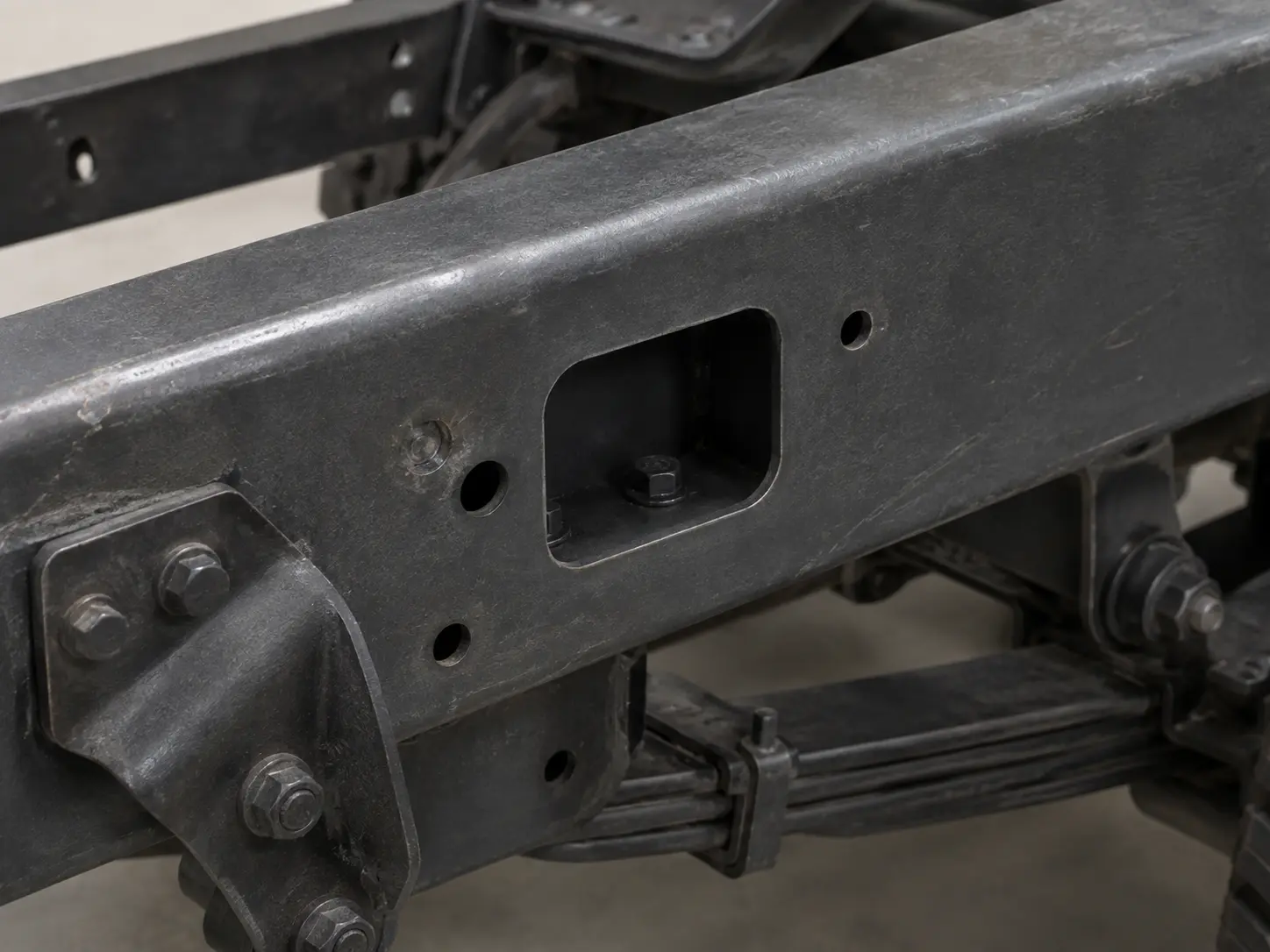 Square access holes cut into a frame rail